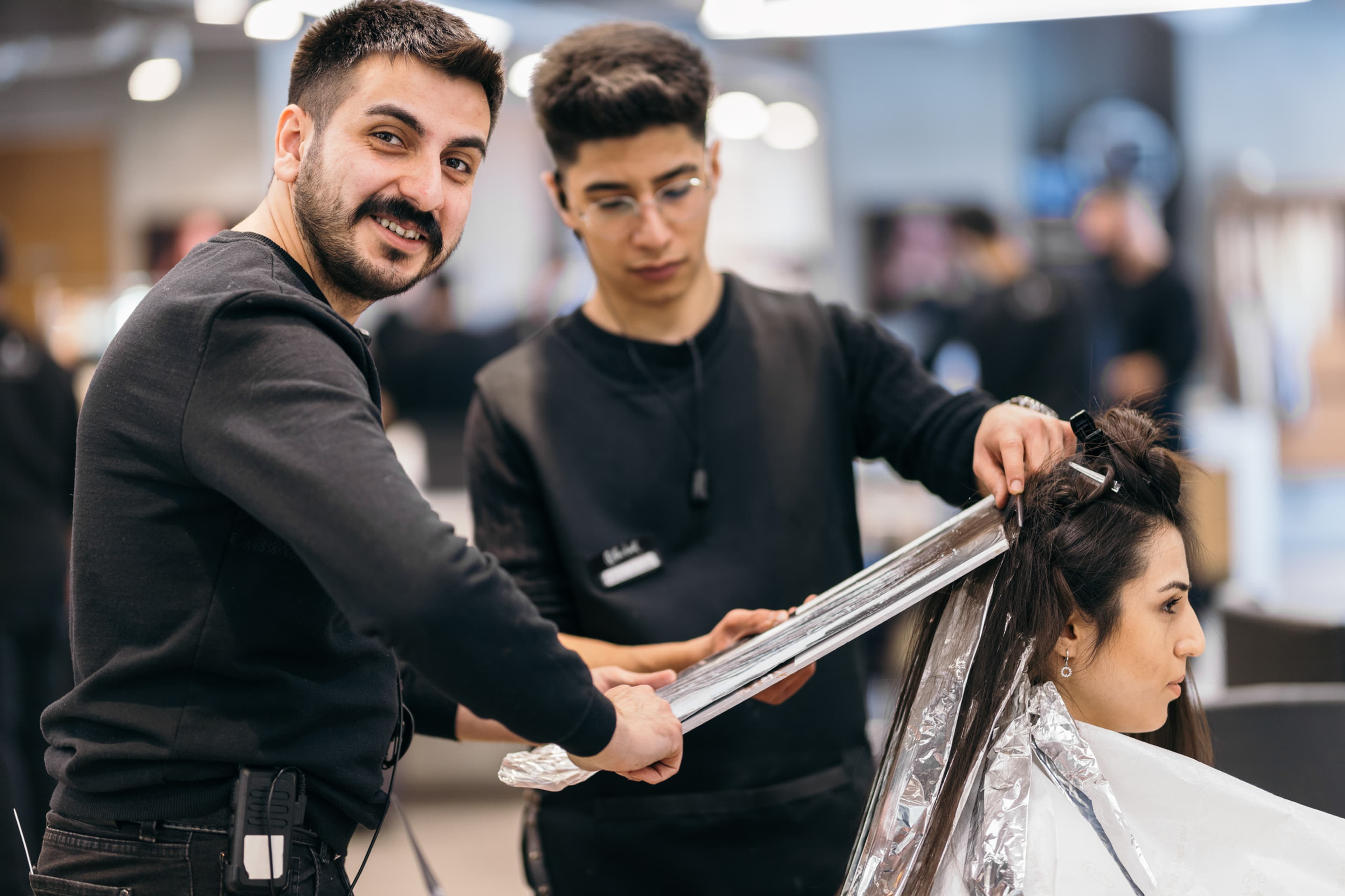 Vue en plongée d’un apprenti coiffeur en formation pratique